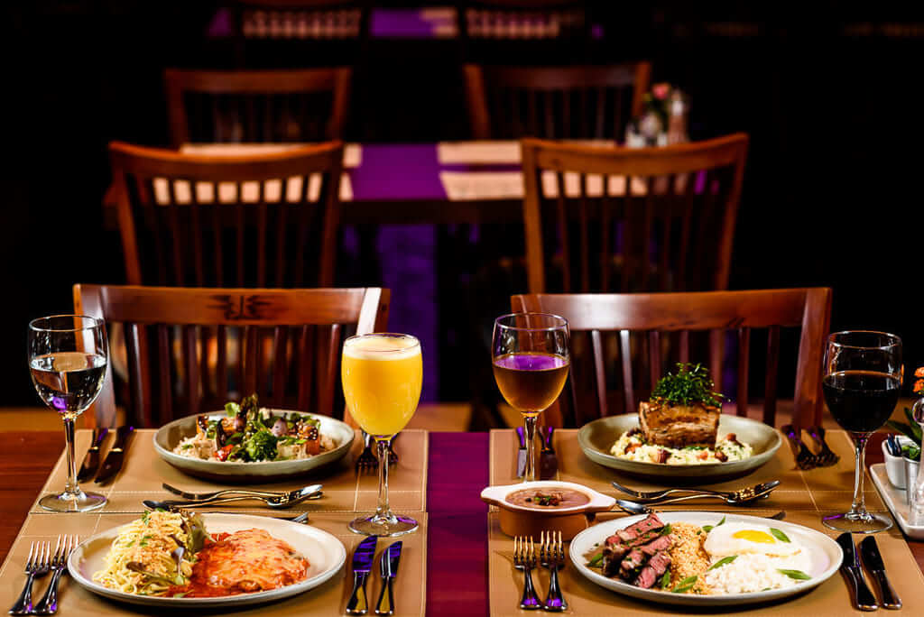 mesa com duas cadeiras com pratos de comida e drinks em salão para eventos em Curitiba