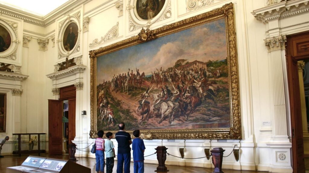 Pessoas apreciando um quadro no Museu Paulista.