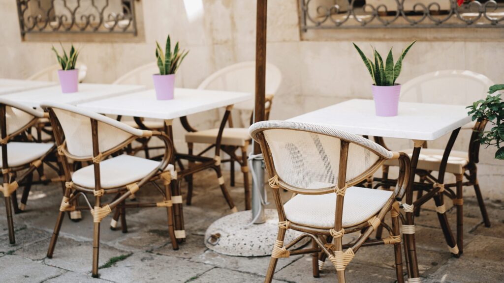Mesas nas calçadas decoradas com uma planta.