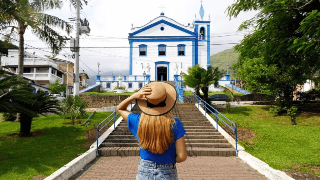 Mulher usando chapéu observando uma igreja azul.