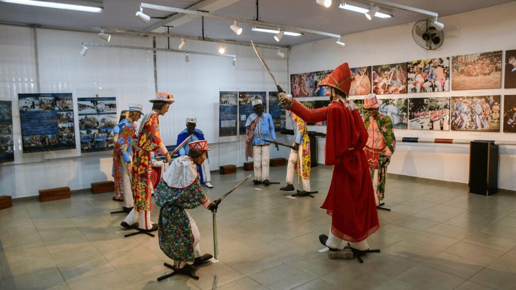 Exposição em um museu com bonecos vestidos em trajes coloridos.
