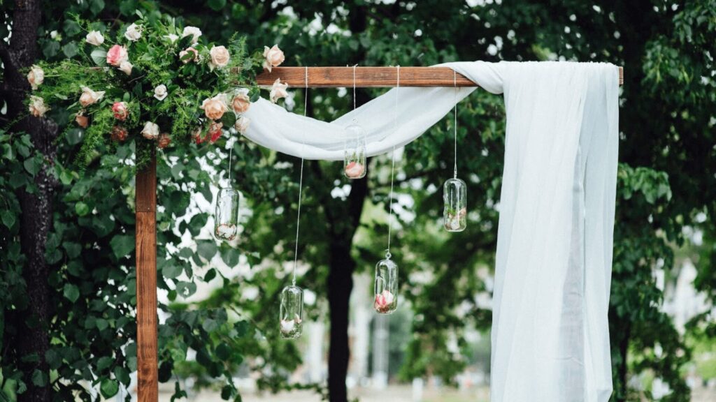 Belo arco de casamento decorado com flores e tecido branco.