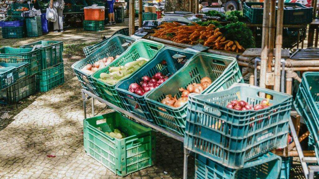 Frutas frescas e legumes à venda em um ambiente de feira ao ar livre.