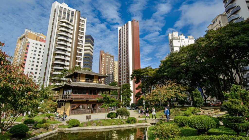 Vista da cidade de Curitiba de um parque cercada por áreas verdes.