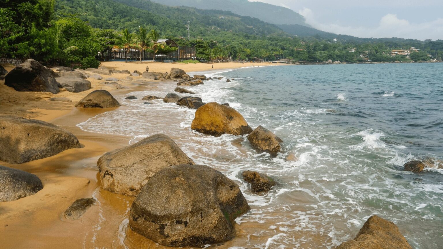 Uma praia serena com rochas e água cristalina, perfeita para uma escapada relaxante.