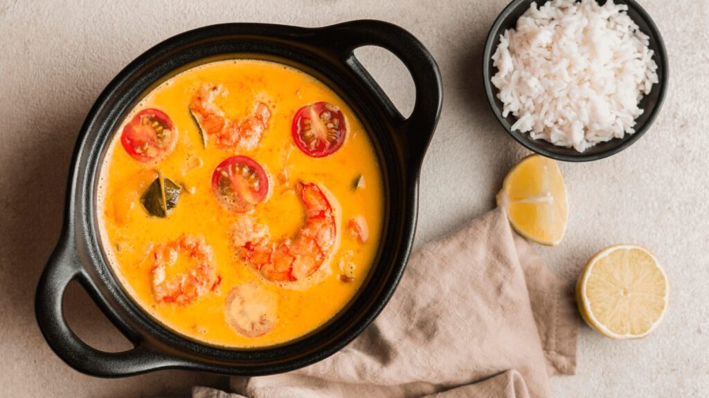 Um delicioso prato de moqueca com camarão e tomate.