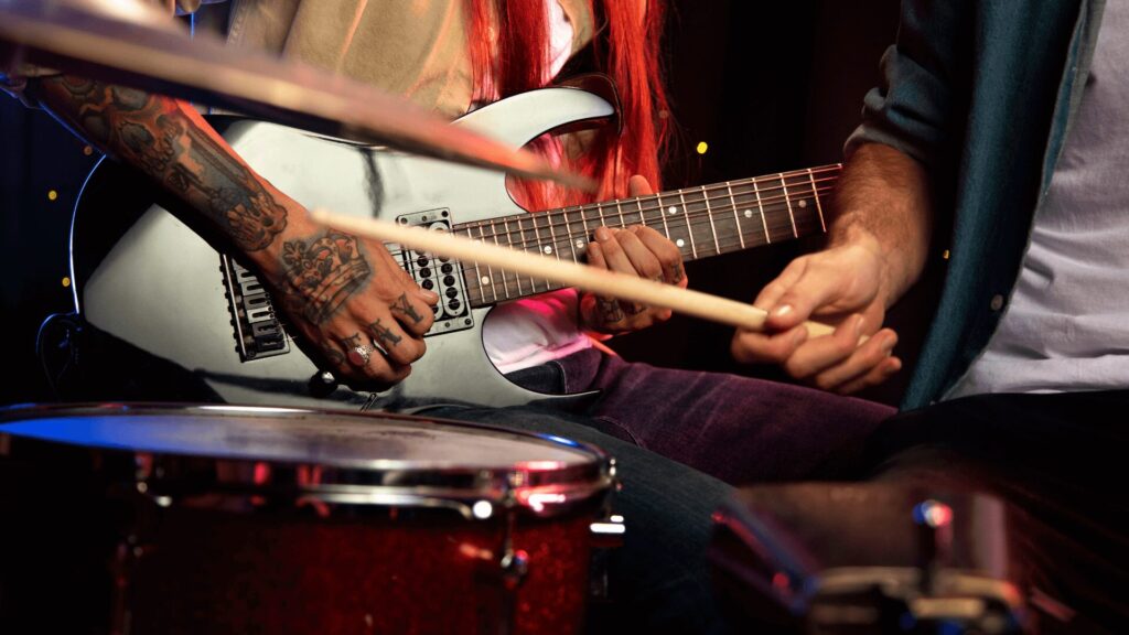 Um guitarrista e um baterista tocando juntos, criando uma música com seus instrumentos.