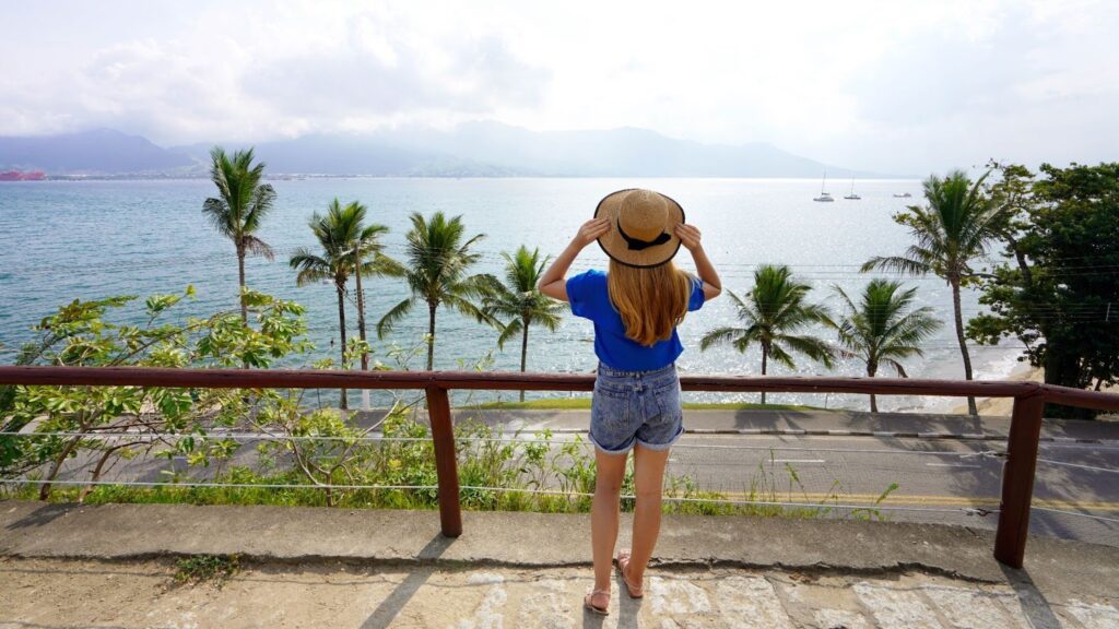 Uma mulher com um chapéu aproveitando a vista do oceano.