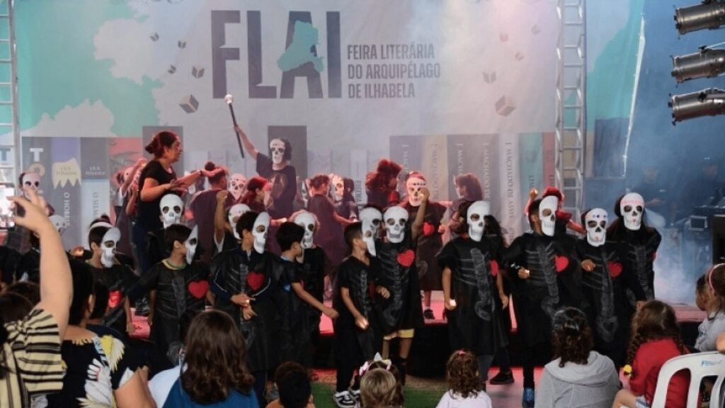Crianças usando máscaras em palco durante uma peça teatral.