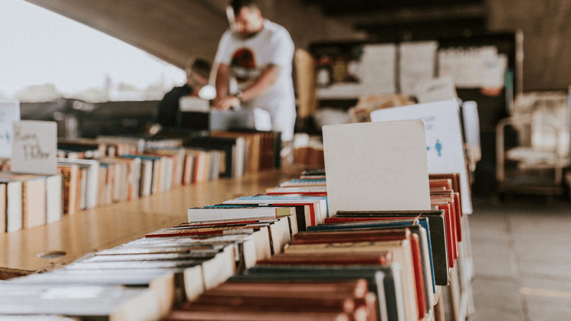 Um homem está olhando para livros em uma mesa.