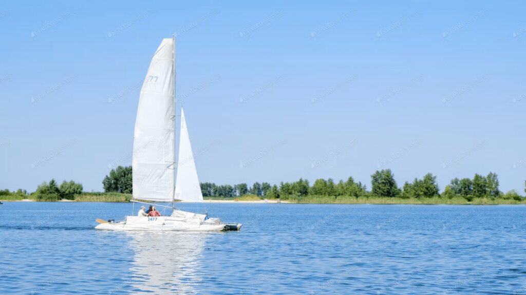 Barco com vela branca navegando tranquilamente.