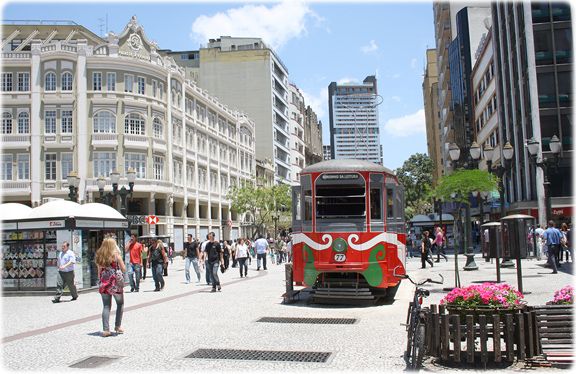 Bondinho histórico entre pedestres em um cenário urbano movimentado com arquitetura clássica.