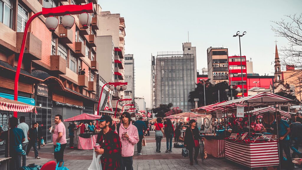 Várias pessoas transitando por uma rua, demonstrando um momento de socialização e movimento na cidade.