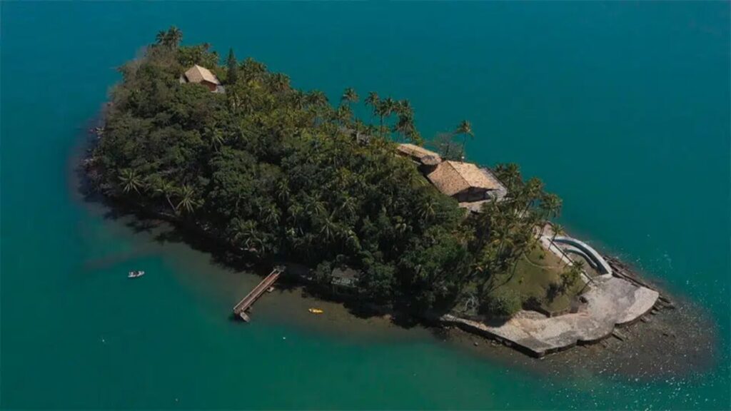 Uma casa tranquila localizada no centro de uma ilha, cercada por um vasto oceano azul, criando um cenário sereno.