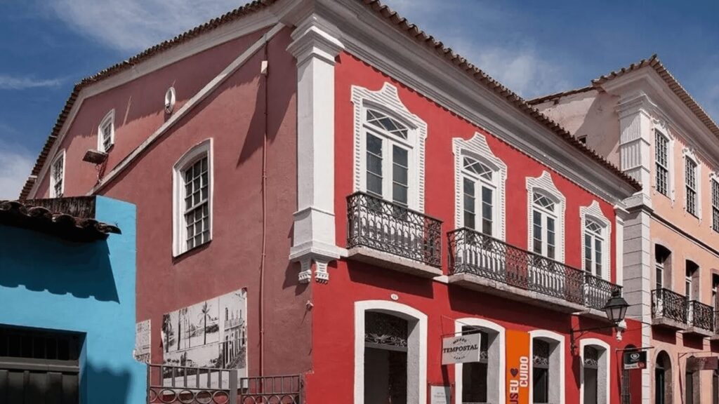 Edifícios coloniais coloridos com janelas tradicionais e varandas de ferro forjado num dia ensolarado.