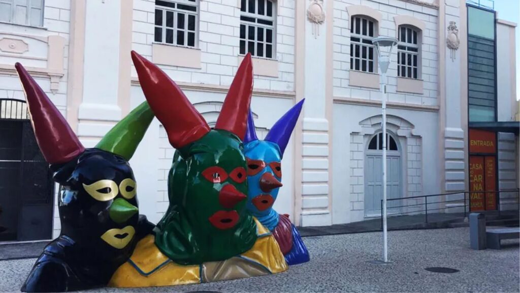 Esculturas coloridas com chifres em frente a um edifício tradicional.