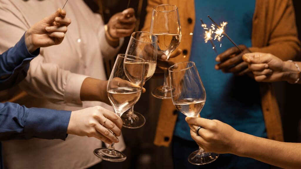 Pessoas tilintando taças de champanhe com faíscas em uma atmosfera festiva.