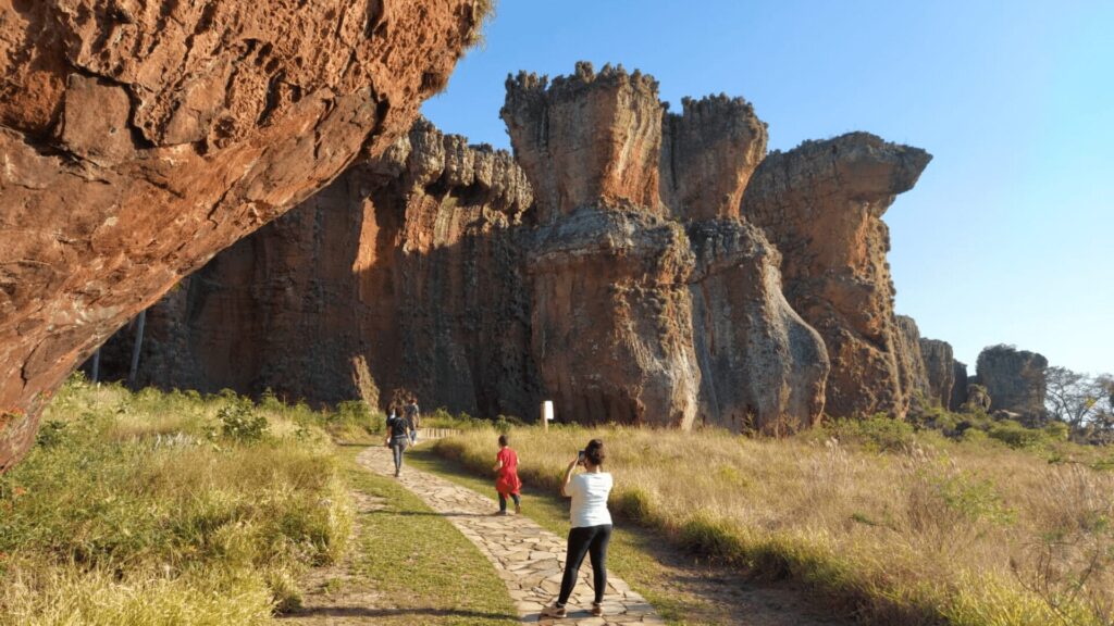 Uma formação rochosa imponente e única no Parque Estadual de Vila Velha, Paraná. O arenito esculpido pela natureza ao longo de milhões de anos é o destaque da imagem, contrastando com o céu azul e a vegetação verde ao redor.