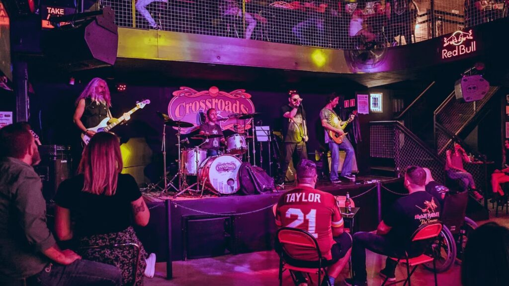 Banda se apresentando no palco em um local com membros da plateia assistindo.