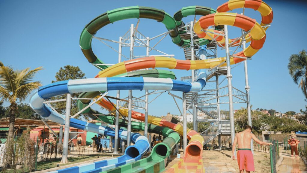 Um vibrante complexo de escorregadores de parque aquático com espirais multicoloridas e uma alta torre de escorregadores sob um céu azul claro.