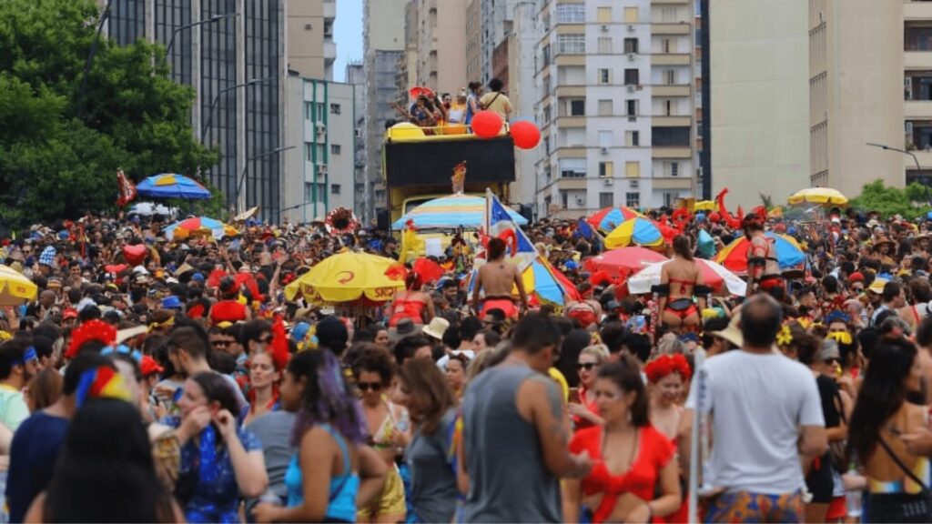 Um festival de rua vibrante repleto de um público diversificado, guarda-chuvas coloridos, fantasias e uma atmosfera festiva em um ambiente urbano.