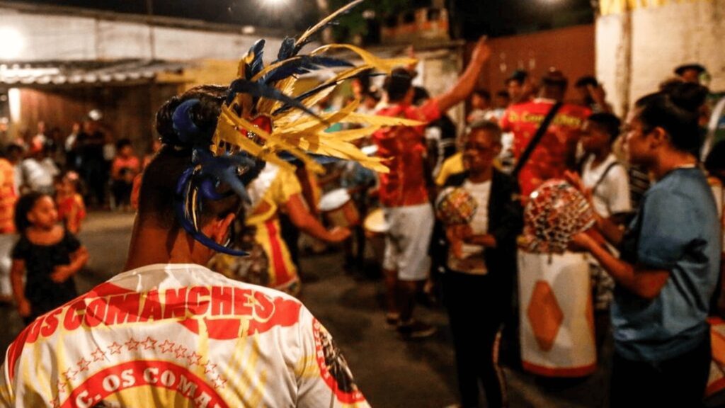 Um cenário vibrante de festival de rua com músicos tocando bateria e dançarinos em trajes coloridos, apresentando uma animada celebração cultural.